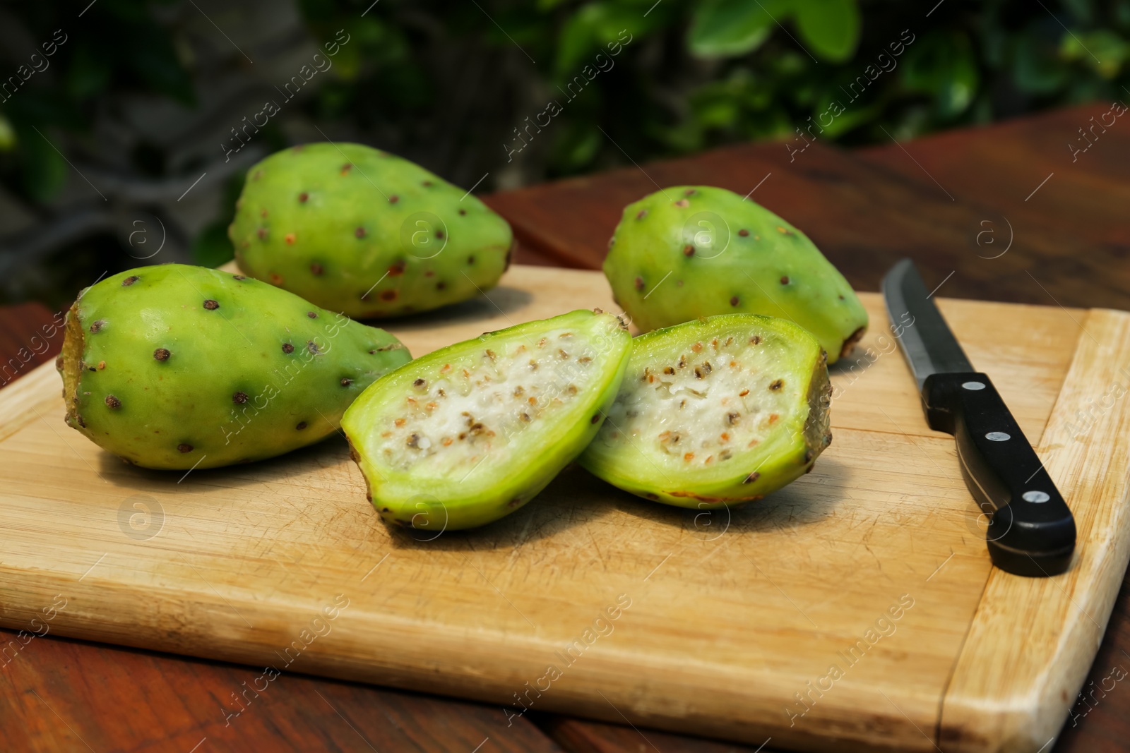 Photo of Tasty prickly pear fruits on wooden table outdoors