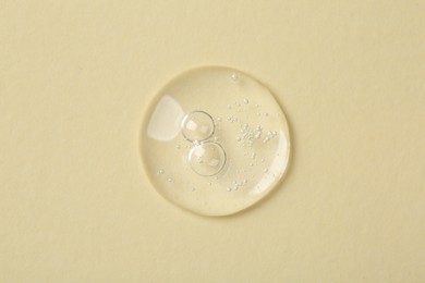 Photo of Sample of cosmetic serum on beige background, top view