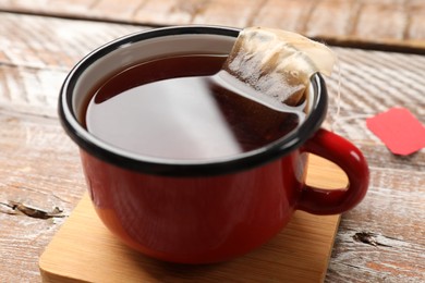 Photo of Tea bag in cup with hot drink on wooden rustic table, closeup