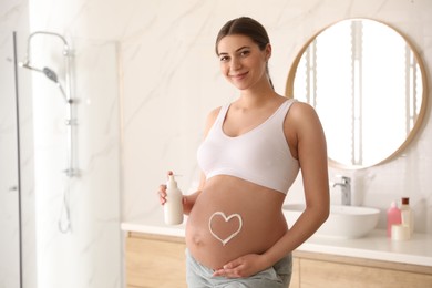 Photo of Young pregnant woman with cosmetic product in bathroom