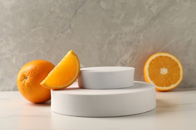 Photo of Presentation for product. Podium and tasty fresh oranges on white table, space for text