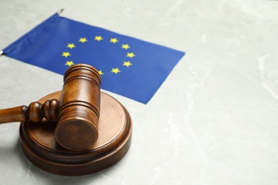 Photo of Judge's gavel and flag of European Union on light grey marble table. Space for text
