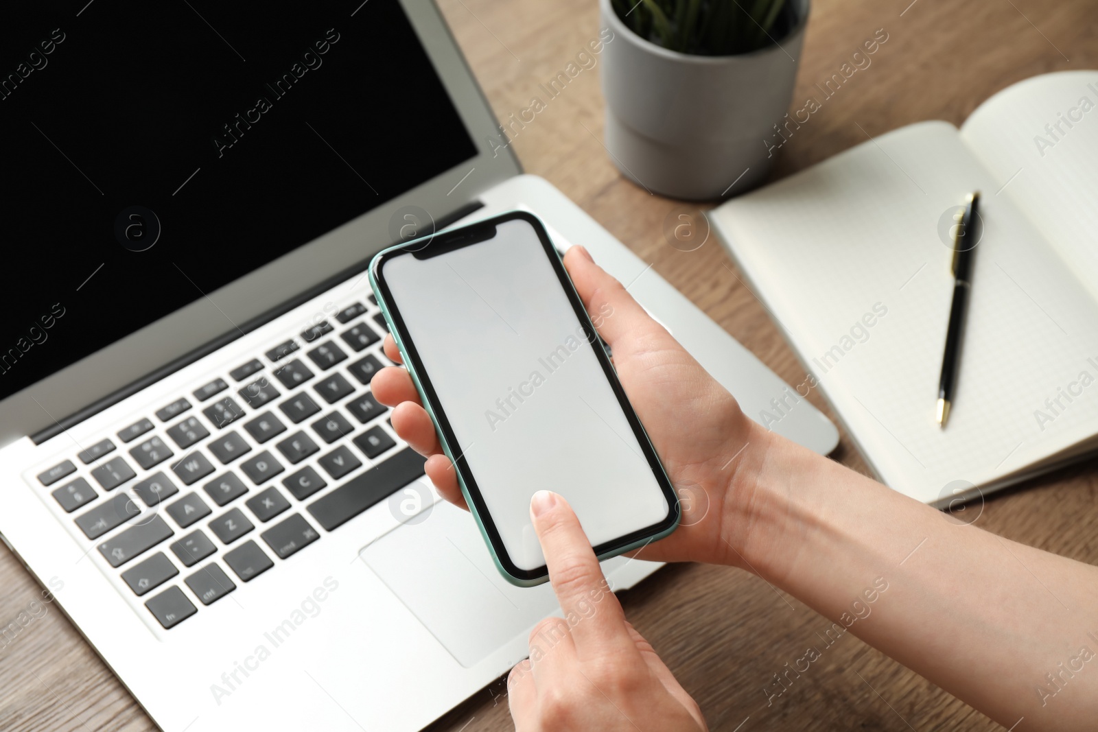 Photo of MYKOLAIV, UKRAINE - JULY 8, 2020: Woman using Iphone 11 Pro Max with blank screen at workplace, closeup