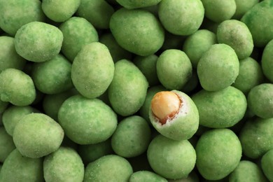 Tasty wasabi coated peanuts as background, top view