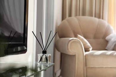 Photo of Aromatic reed air freshener on tv table at home, space for text