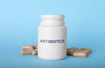 Image of Plastic bottle with antibiotic pills on light blue background