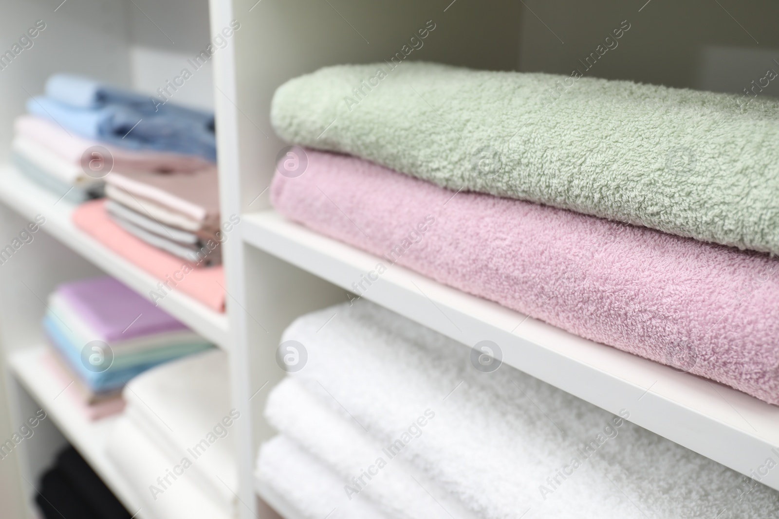 Photo of Different terry towels on shelves in linen shop, closeup. Space for text
