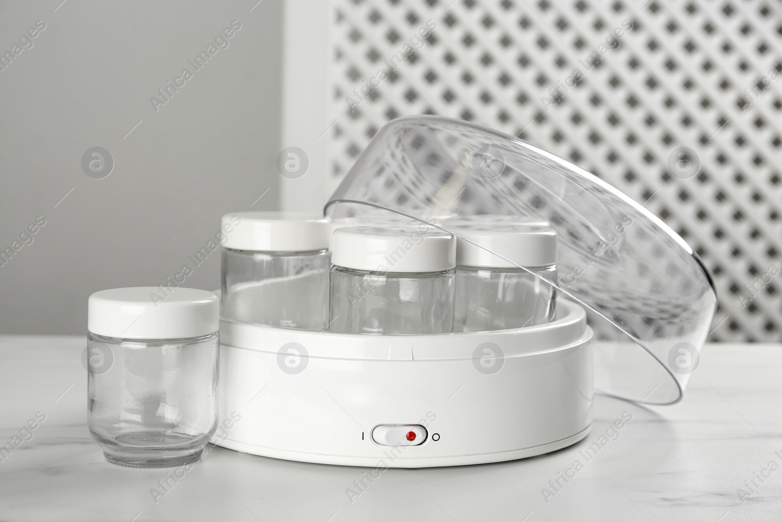 Photo of Modern yogurt maker with empty jars on white table indoors