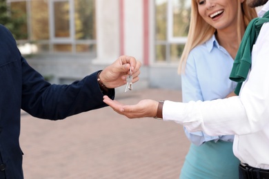 Male real estate agent giving house key to couple outdoors