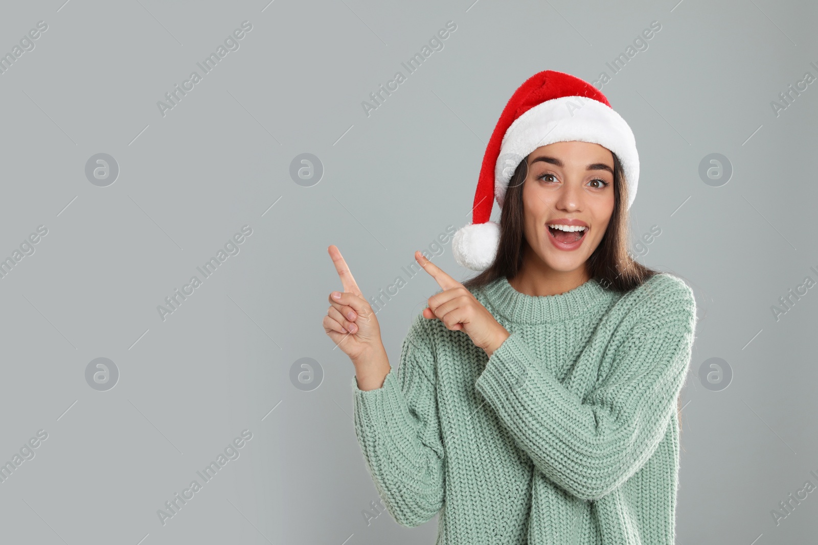 Photo of Happy woman in Santa hat on grey background, space for text. Christmas countdown