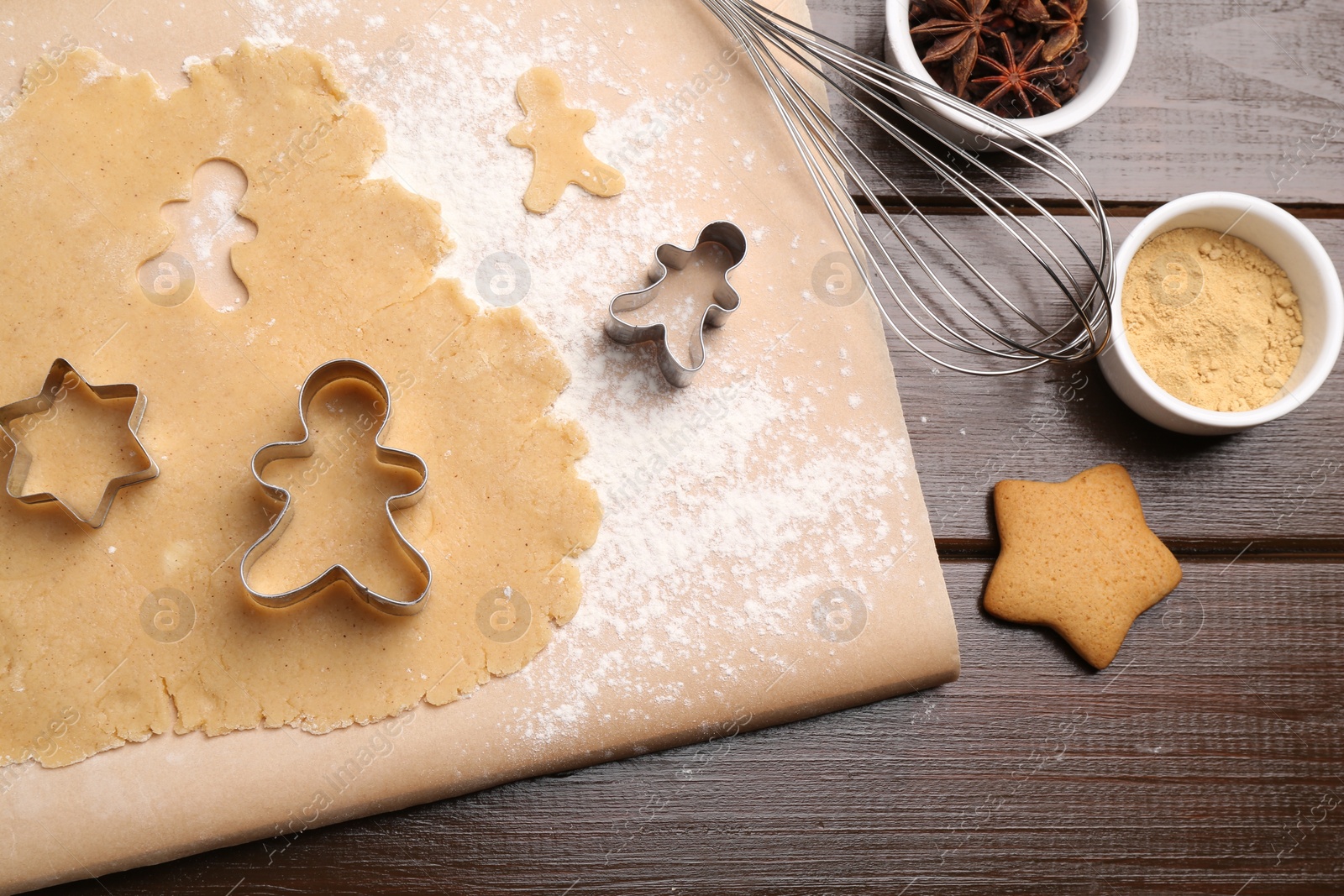 Photo of Making Christmas cookies. Cutters, ingredients and raw dough on wooden table, flat lay