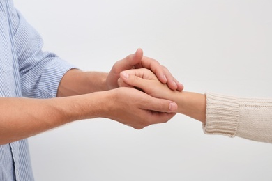 Photo of Man holding woman's hand on light background. Concept of support and help