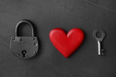 Padlock, wooden heart and key on black stone background, flat lay. Relationship problems concept