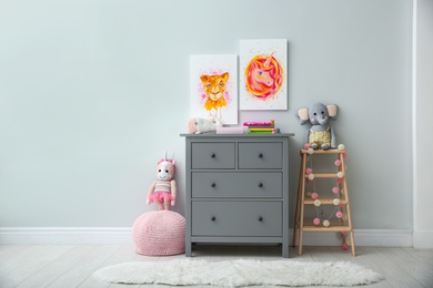 Photo of Cute pictures and chest of drawers with toys in baby room interior. Space for text