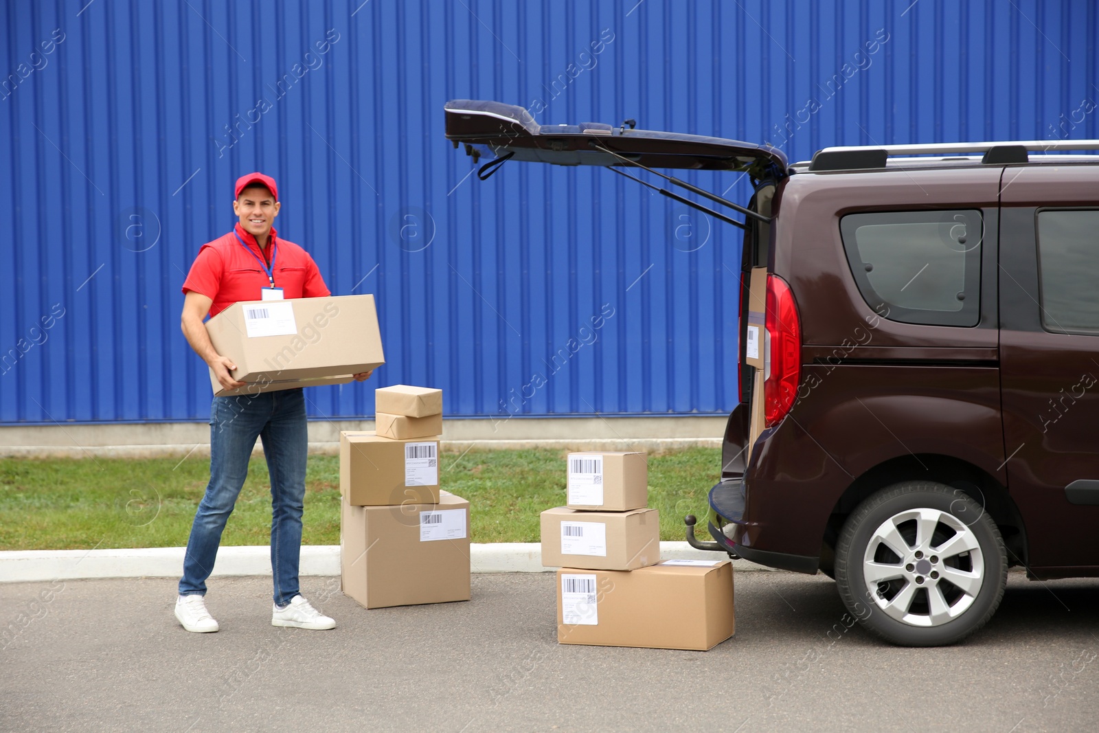 Photo of Courier loading packages in car trunk outdoors