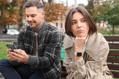 Man ignoring his girlfriend and using smartphone outdoors. Relationship problems