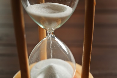 Hourglass with flowing sand on table, closeup. Time management