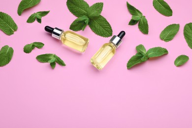 Photo of Bottles of essential oil and mint on pink background, flat lay. Space for text