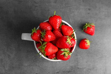 Photo of Mug with ripe red strawberries on grey background, top view