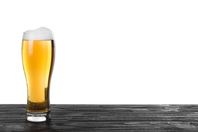 Glass of tasty beer on black wooden table against white background