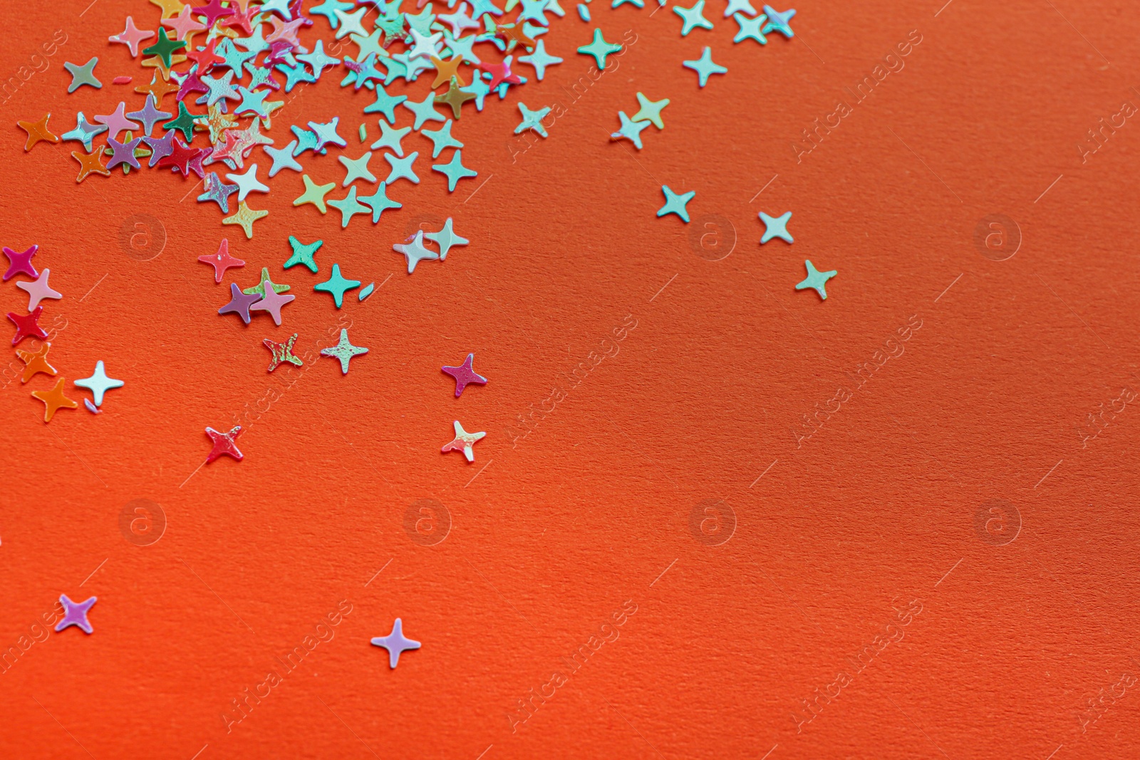 Photo of Shiny bright colorful glitter on orange background. Space for text
