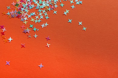 Photo of Shiny bright colorful glitter on orange background. Space for text