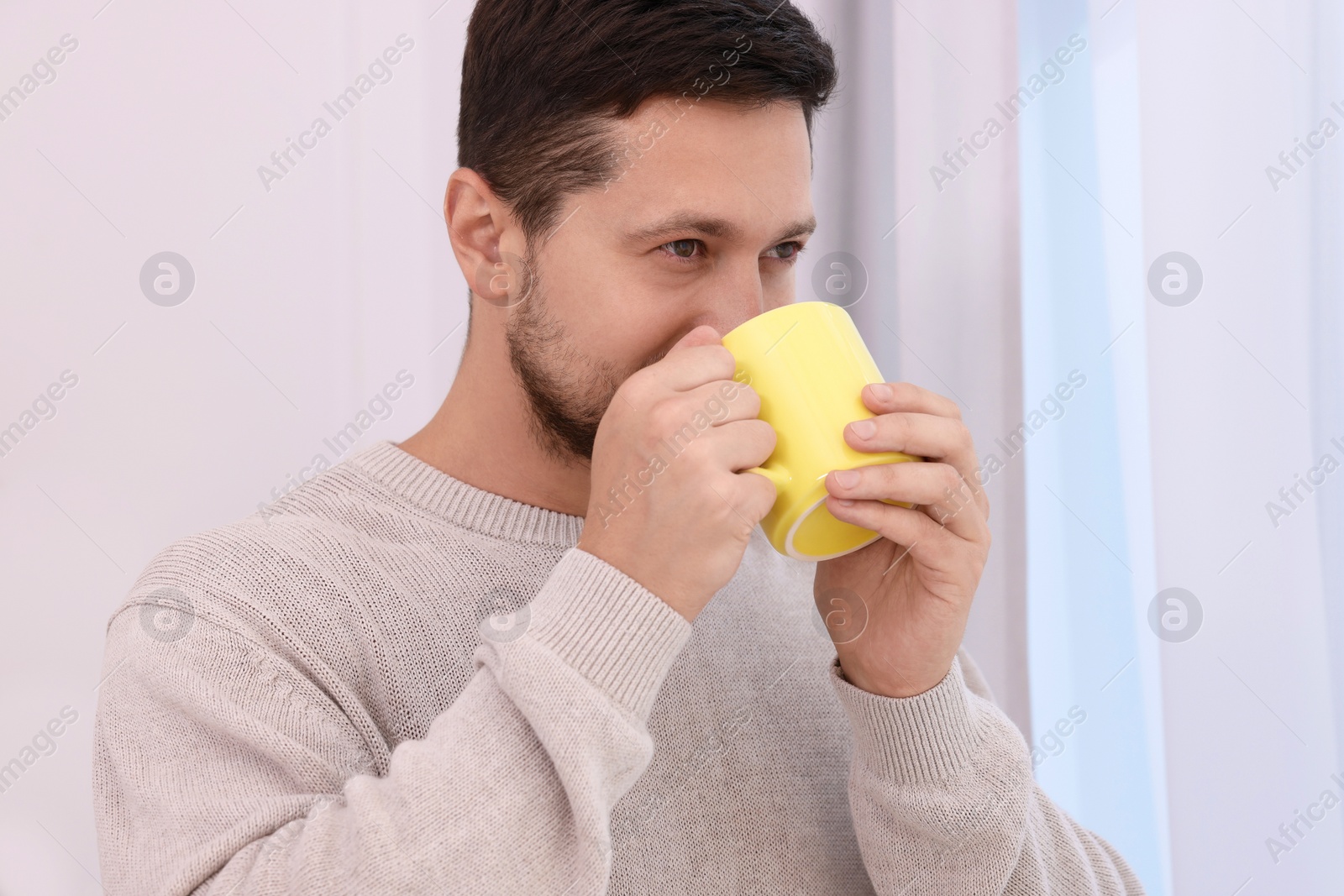 Photo of Man drinking from yellow mug at home