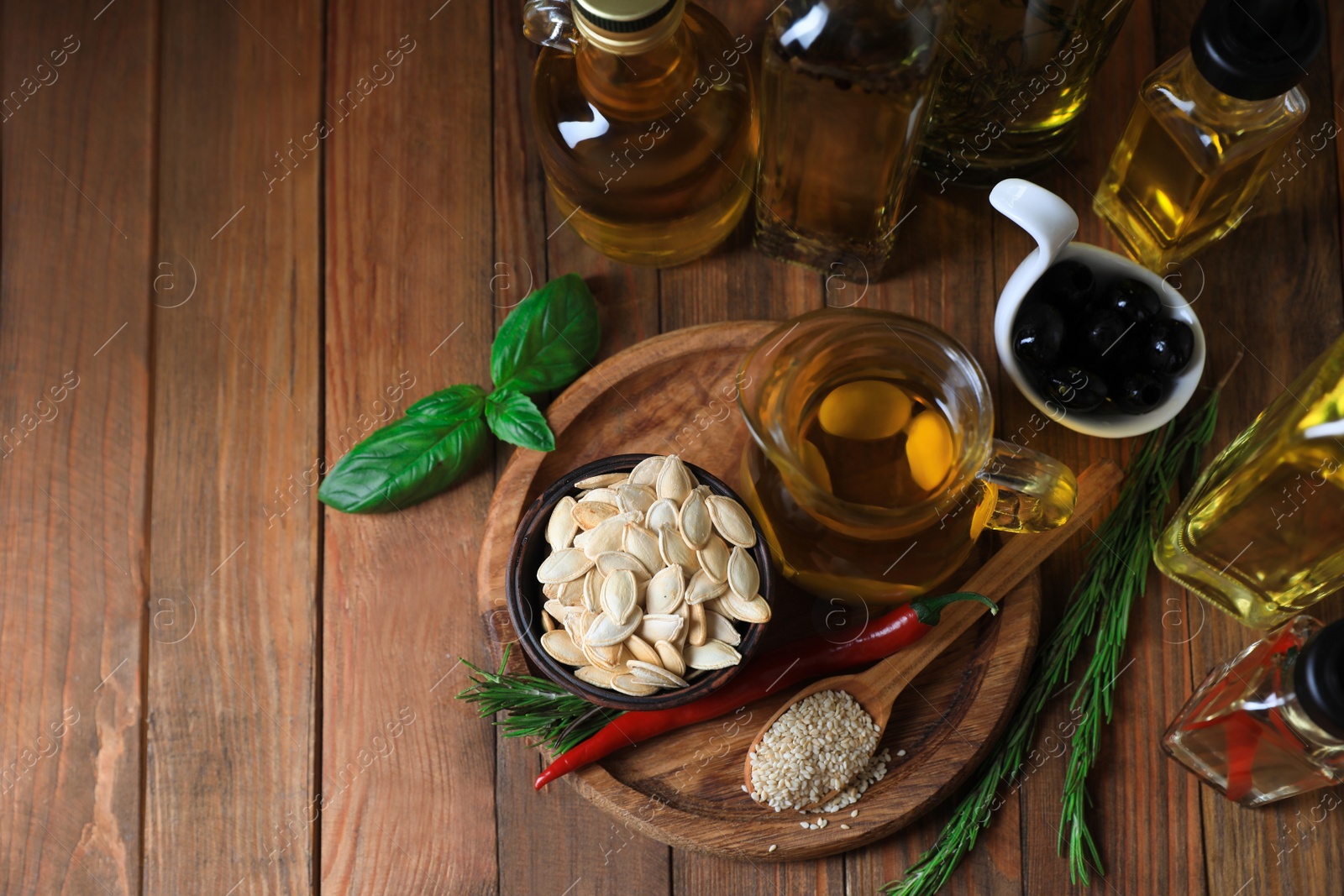 Photo of Different cooking oils and ingredients on wooden table, flat lay. Space for text