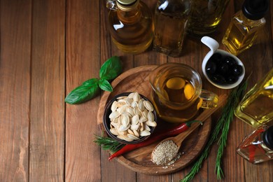 Different cooking oils and ingredients on wooden table, flat lay. Space for text