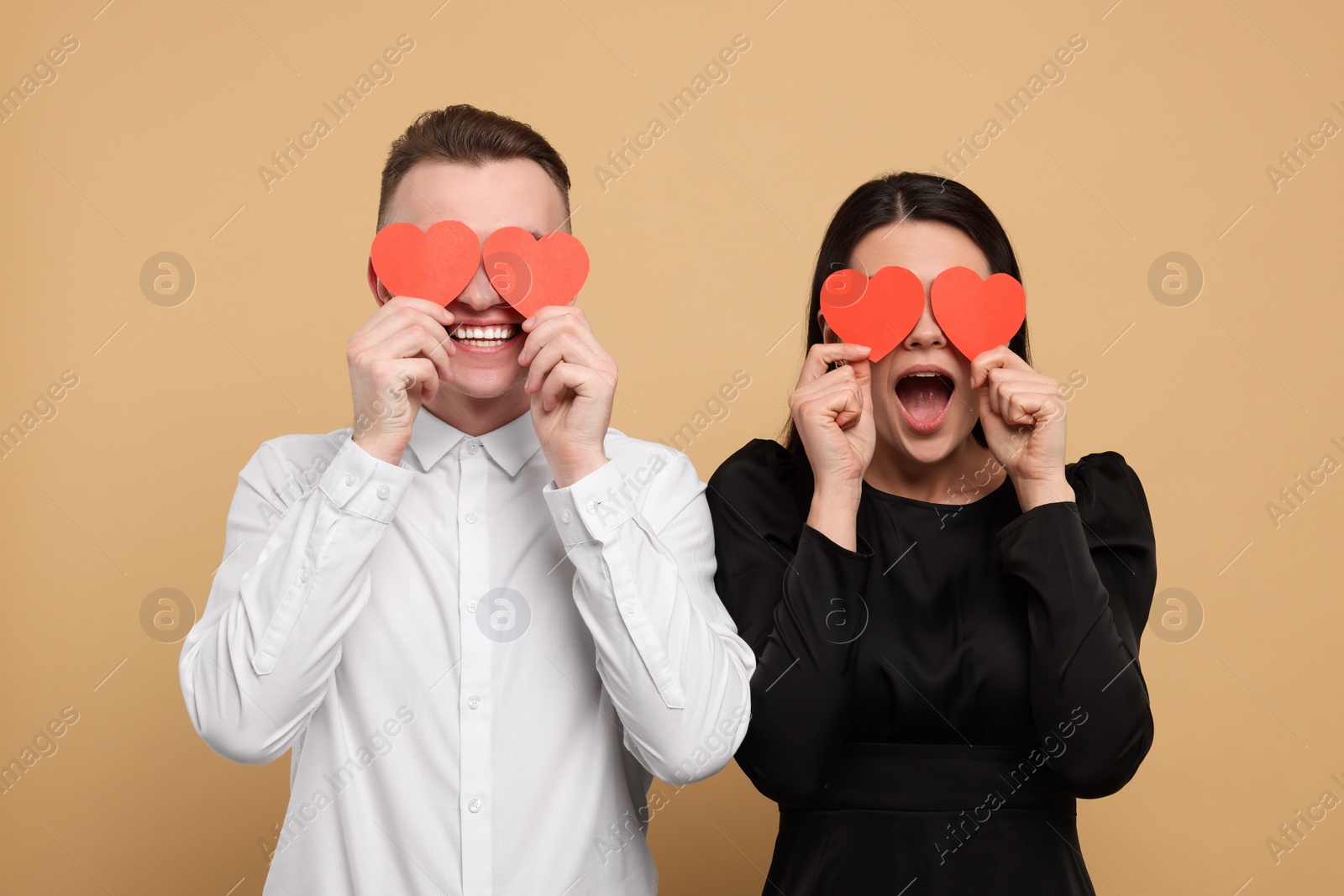 Photo of Lovely couple with decorative hearts on beige background. Valentine's day celebration