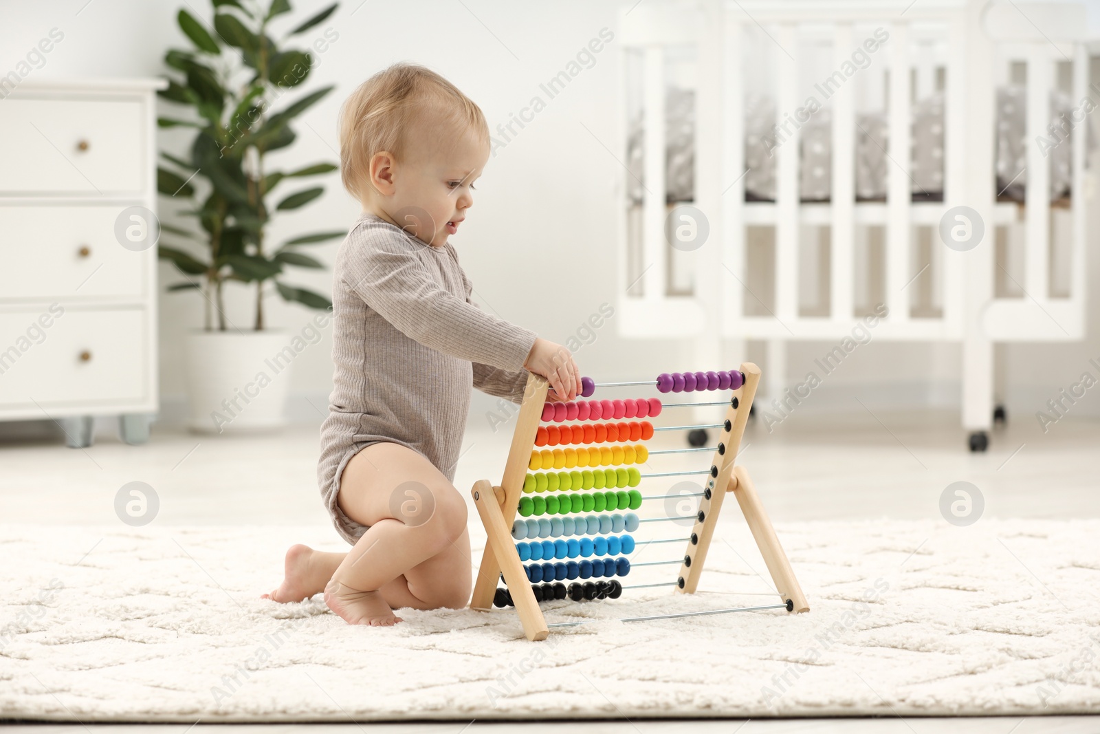 Photo of Children toys. Cute little boy playing with wooden abacus on rug at home