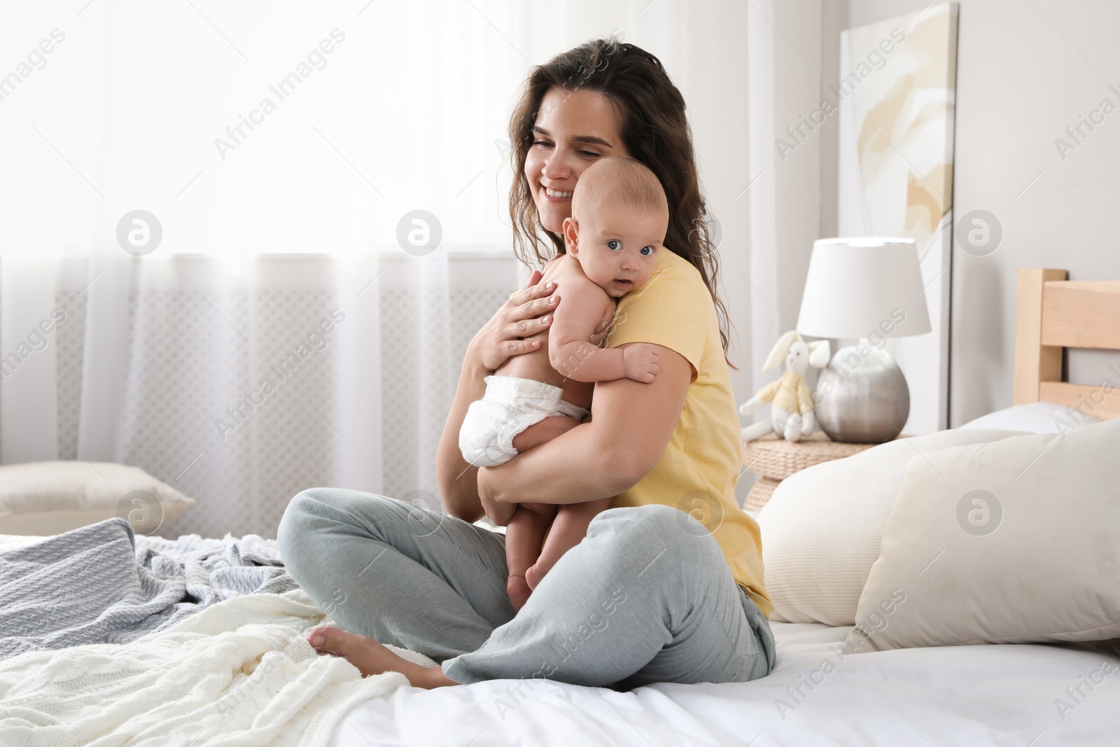 Photo of Happy young mother with her cute baby on bed at home