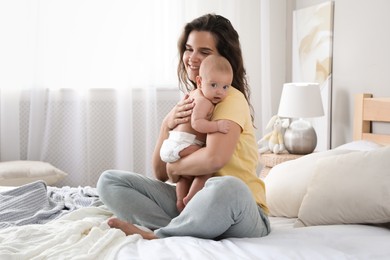 Photo of Happy young mother with her cute baby on bed at home