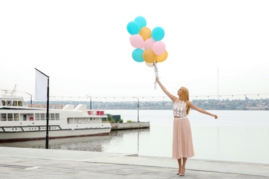 Photo of Beautiful young woman with bunch of balloons outdoors. Space for text