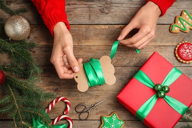 Woman wrapping Christmas gift at wooden table, top view