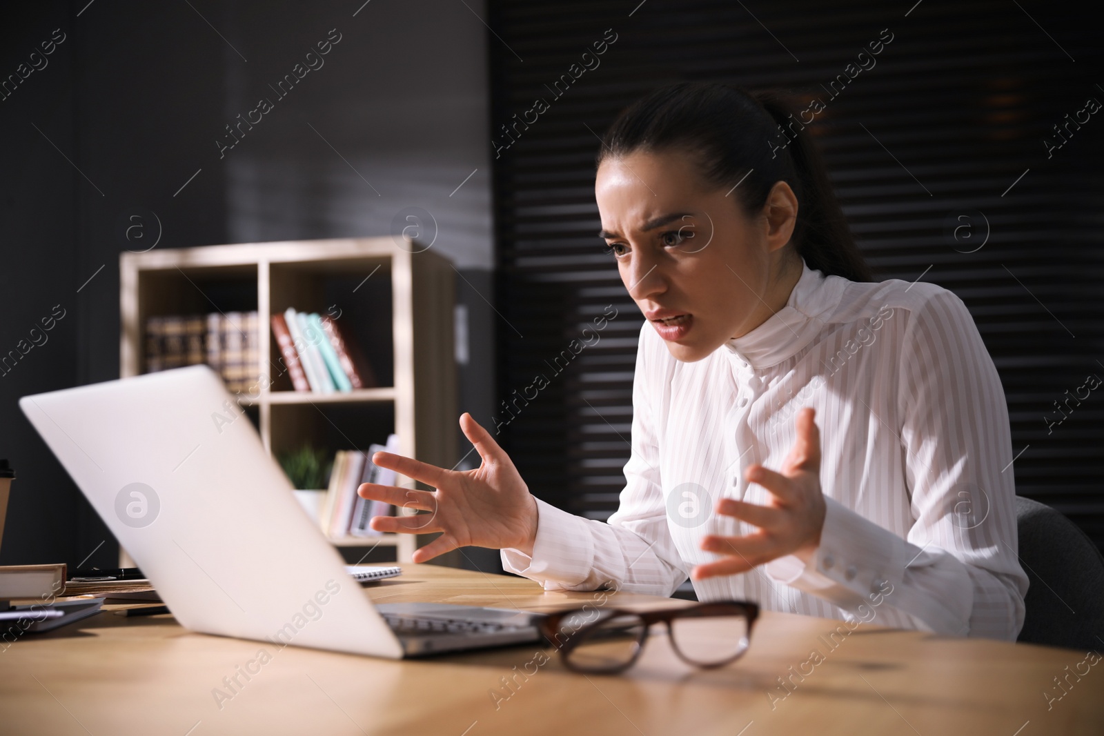 Photo of Emotional young businesswoman working on laptop in office. Online hate concept