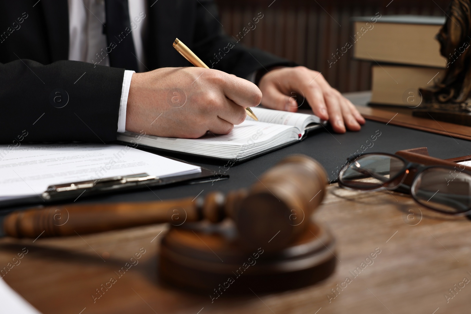 Photo of Lawyer taking notes at wooden table, closeup