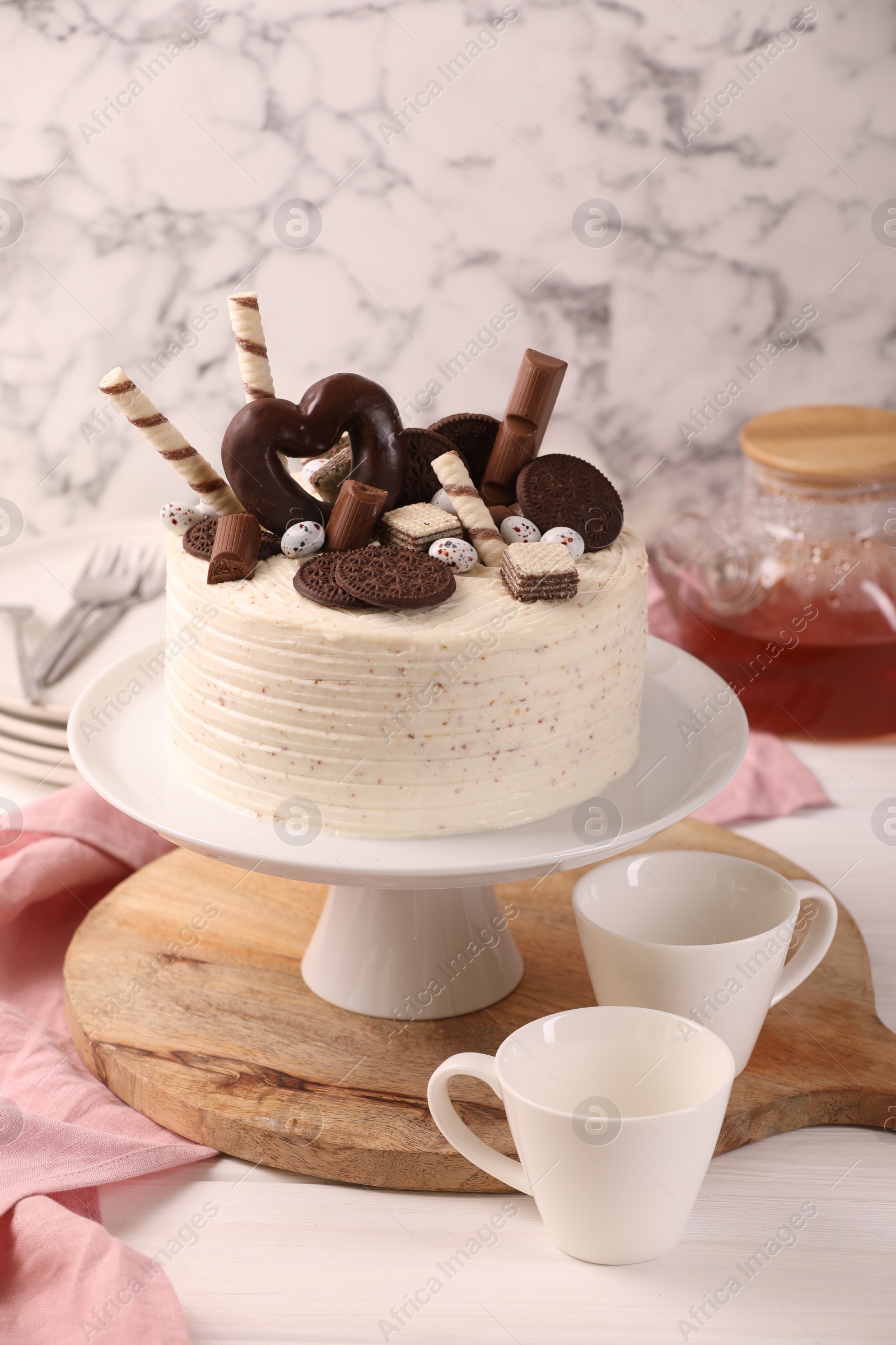 Photo of Delicious cake decorated with sweets served on white table