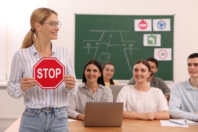 Teacher showing Stop road sign during lesson in driving school