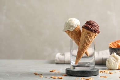 Tasty ice cream scoops in waffle cones on grey marble table, closeup. Space for text