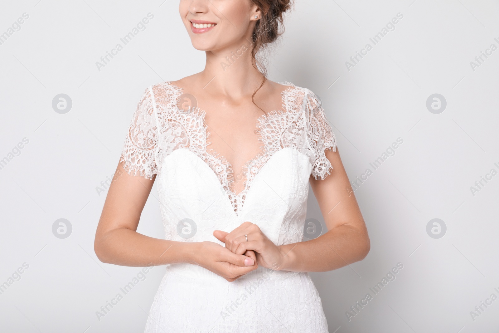 Photo of Young bride wearing beautiful wedding dress on light grey background, closeup