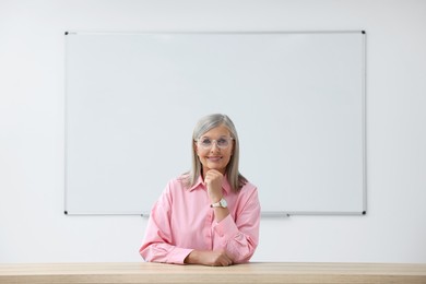 Portrait of professor sitting at desk in classroom