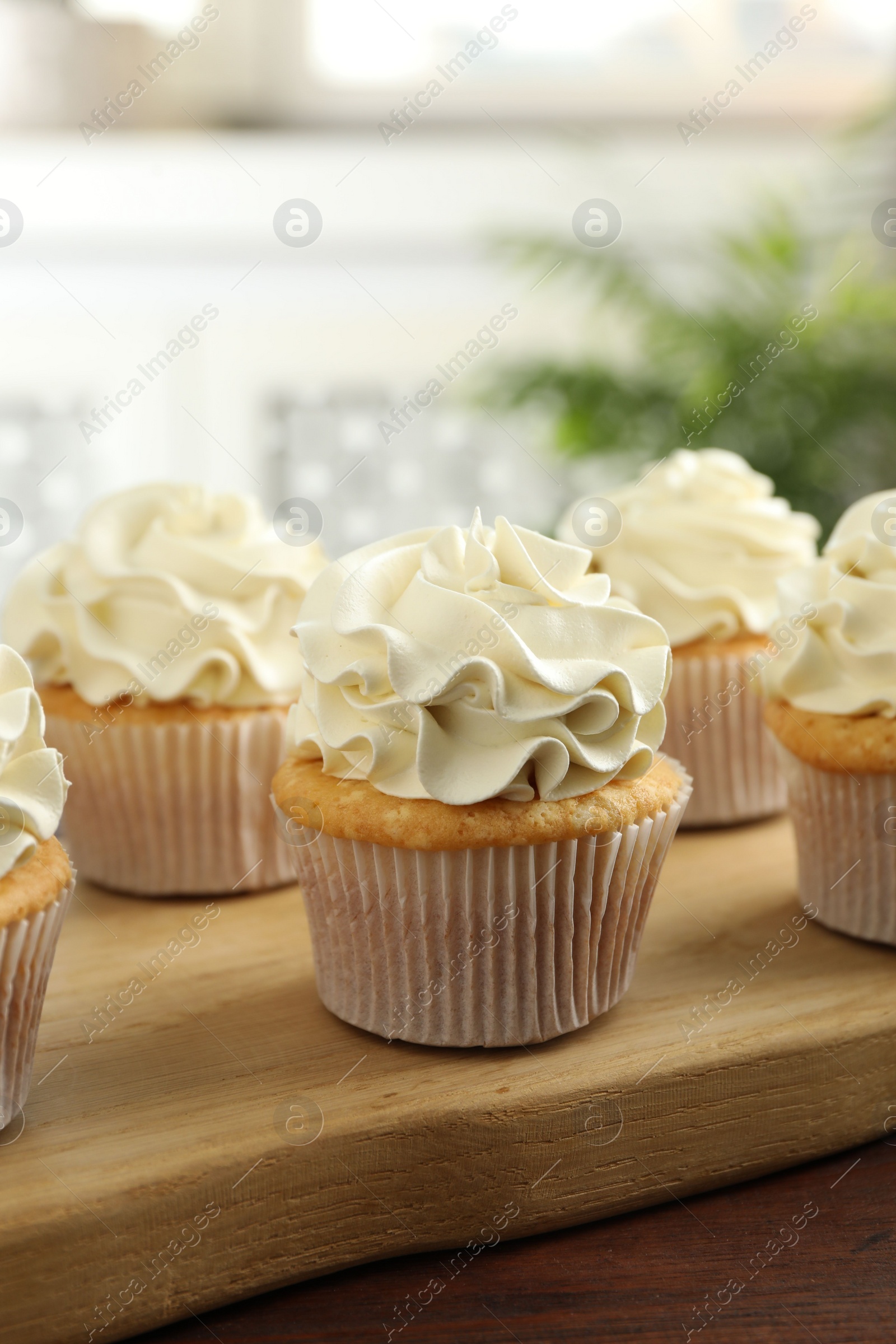 Photo of Tasty cupcakes with vanilla cream on wooden table, closeup