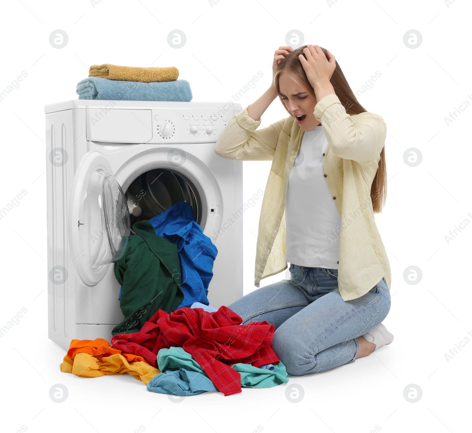 Photo of Upset woman with dirty clothes near washing machine on white background