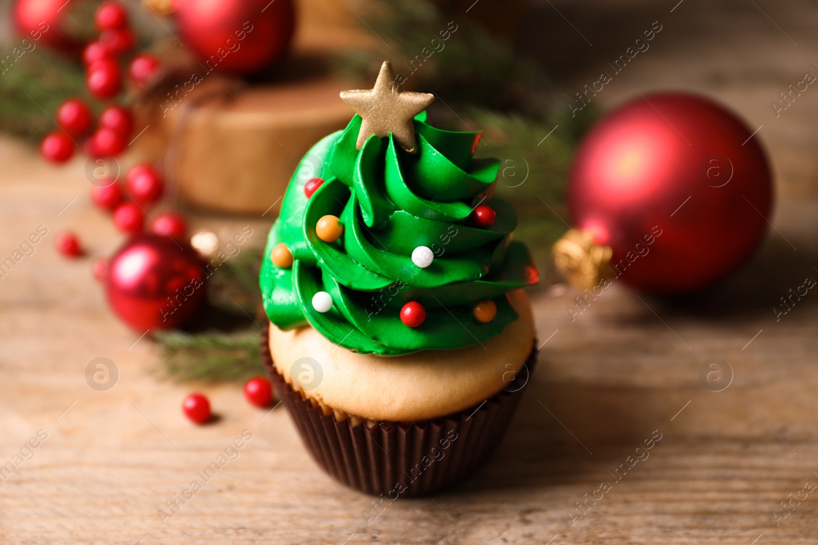 Photo of Christmas tree shaped cupcake on wooden table, closeup