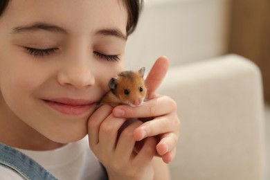 Photo of Little girl hugging cute hamster at home, closeup