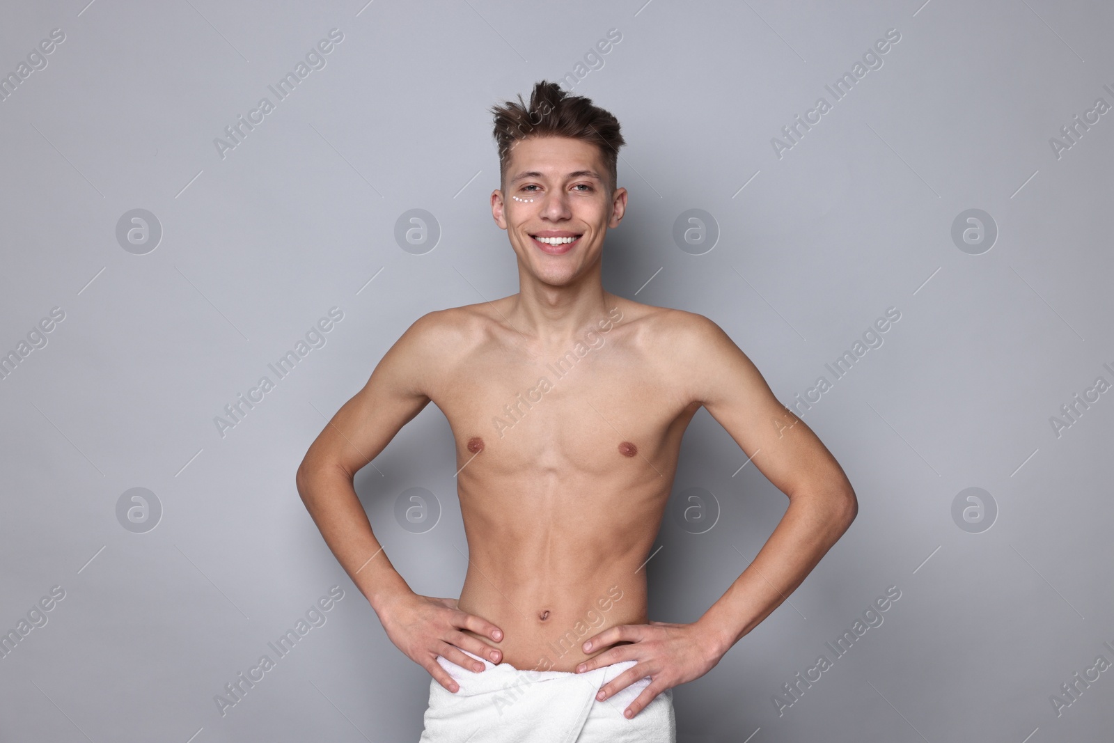 Photo of Handsome man with moisturizing cream on his face against light grey background