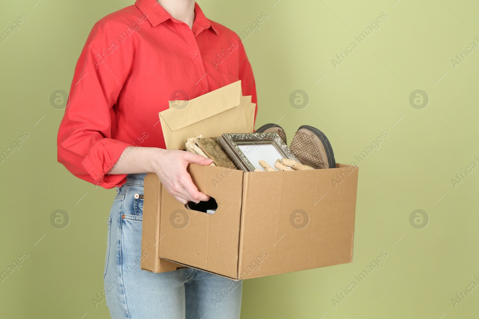 Photo of Woman holding box of unwanted stuff on green background, closeup