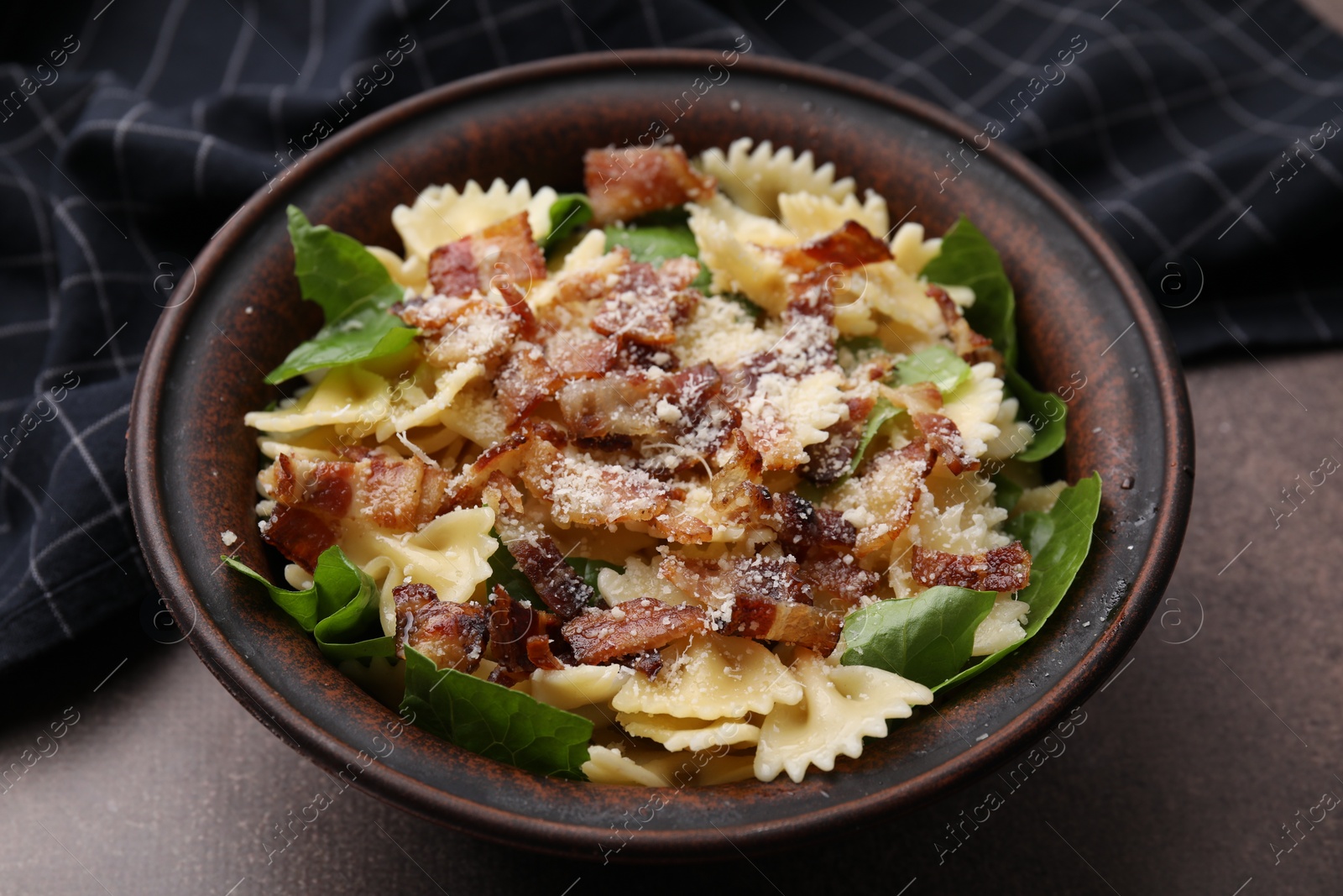 Photo of Tasty pasta with bacon and basil on brown table