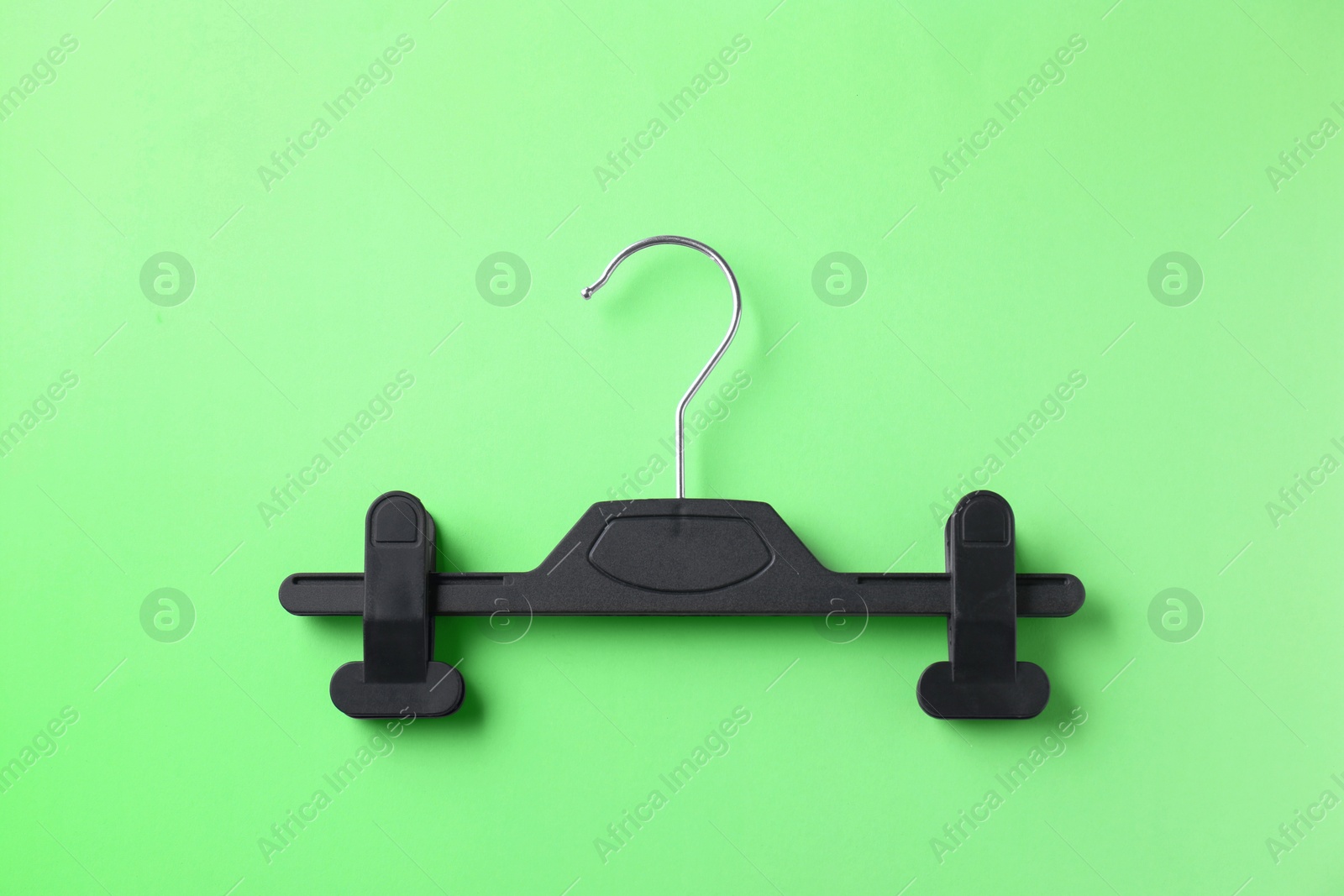 Photo of Black hanger with clips on light green background, top view